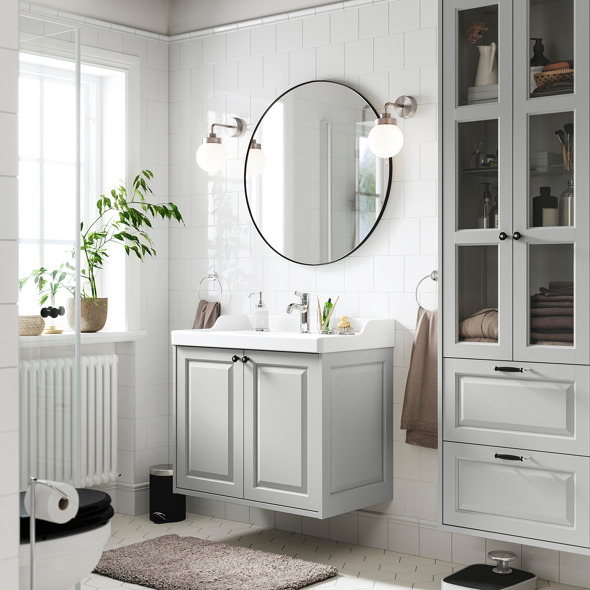 Moderne badeværelse med TÄNNFORSEN gråt skab, rundt spejl, glashylder. Rene linjer, klassisk design, rummelig planløsning.
