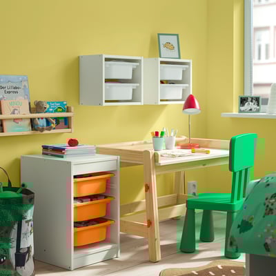 Børneværelse med TROFAST hvid opbevaring, orange skraldespande, grøn stol. Lyst, organiseret rum.