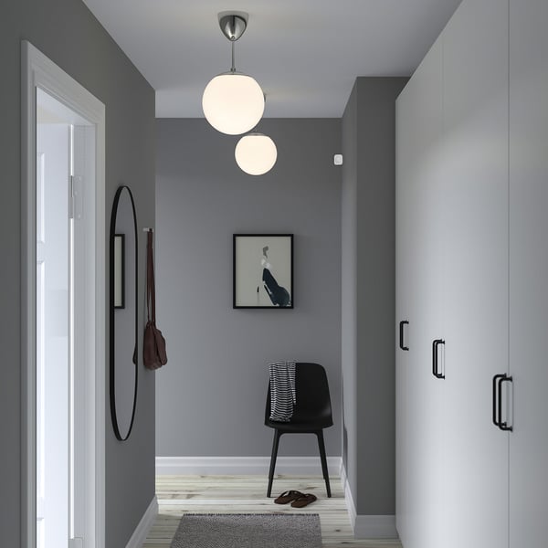 Moderne entré med grå vægge, hvide døre, sort stol, kunst, lys, spejl, tæppe, hjemmesko, diskret bevægelsessensor.