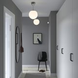 Moderne entré med grå vægge, hvide døre, sort stol, kunst, lys, spejl, tæppe, hjemmesko, diskret bevægelsessensor.