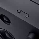 Nærbillede af en slank sort bluetooth-højttaler med en cirkulær lydstyrkeknap og et Bluetooth-forbindelsesikon, der viser et moderne design.