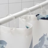 Klar badeforhængsstang, der holder hvidt og blåt gardin med fiskedesign.