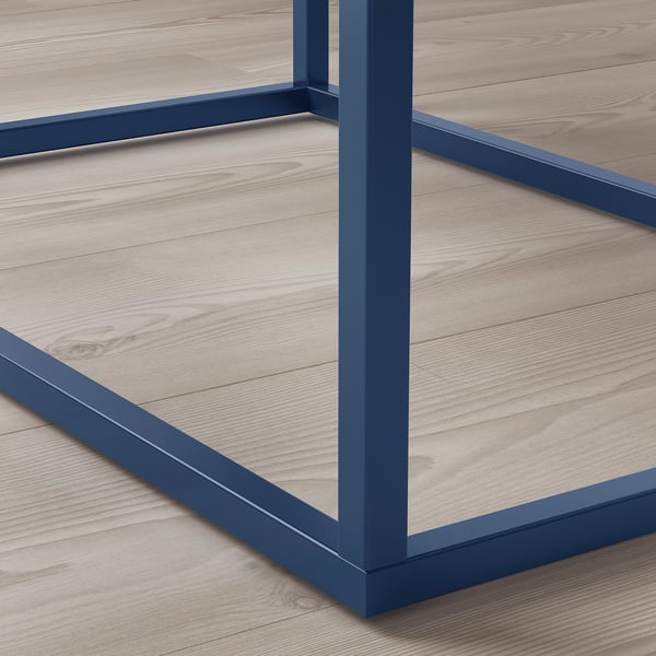 Blå metalramme på et natbord på trægulv. Robust, rent design.