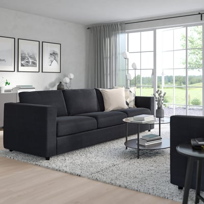 Moderne stue med mørkegrå VIMLE sofa, tre store vinduer, tæppe, borde, lampe, dekorationer.