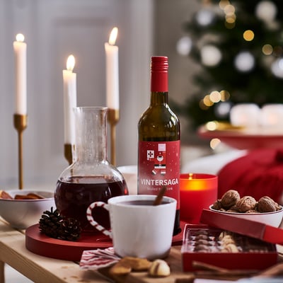 Julescene med VINTERSAGA flaske, stearinlys, kopper og lækkerier.
