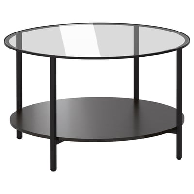 Et moderne VITTSJÖ sofabord med glasplade og sort metalstel med en nederste hylde til opbevaring.