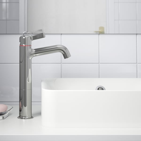 Moderne krom badeværelsesarmatur med håndtag på hvid bordplade, der sparer vand og energi med koldstartfunktion.