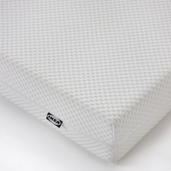 A pristine white IKEA mattress with a textured surface, a zip, and a tag indicating high quality and comfort.