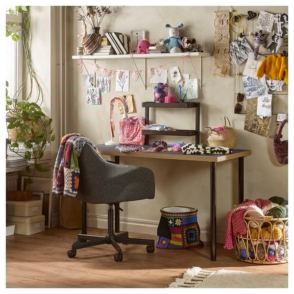 Craft room with chair, desk, yarn, & crochet projects.