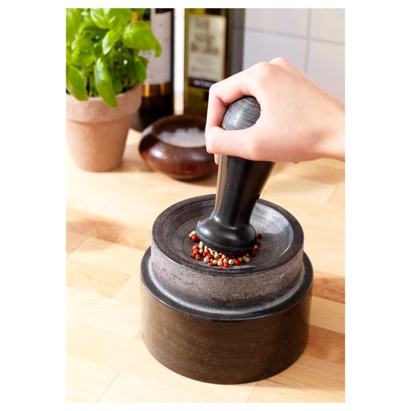 Image a hand grinding peppercorns in a marble mortar and pestle.