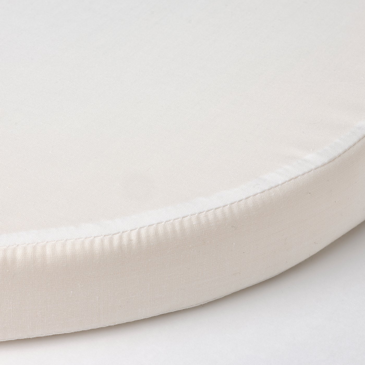 Close-up of a soft, white, round mattress with smooth fabric and clean stitching.