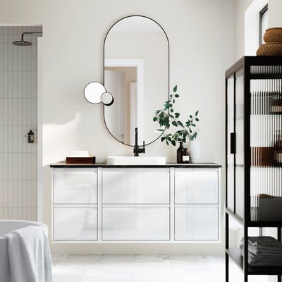 Modern bathroom with ÄNGSJÖN white vanity, large mirror, simple sink, greenery, and shelves.