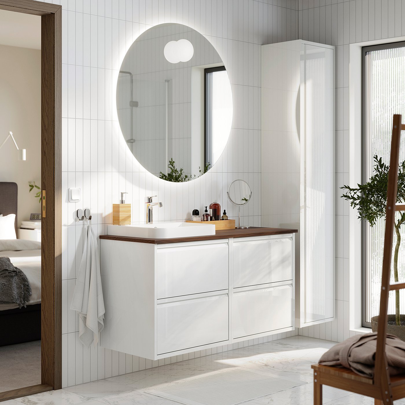 Modern white bathroom with ÄNGSJÖN vanity. Large round mirror, sleek counter, wooden accents. Vanity appears spacious, fits well under mirror.