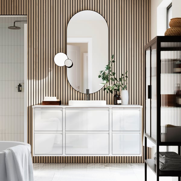 Modern white vanity, striped bathroom, large mirror, drawers, decorative items, black towel shelf.