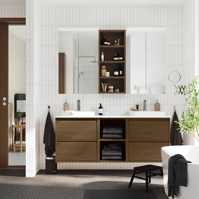 Brown oak bathroom vanity with open/closed storage, double basin, towels, and mirror.