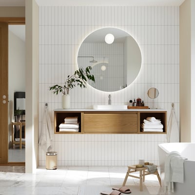 ÄNGSJÖN light wood vanity with round mirror, open/closed storage, white basin, stool, towels.