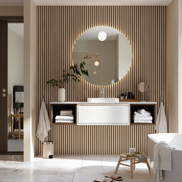 Modern bathroom with floating cabinet, semi-recessed basin, and round mirror.