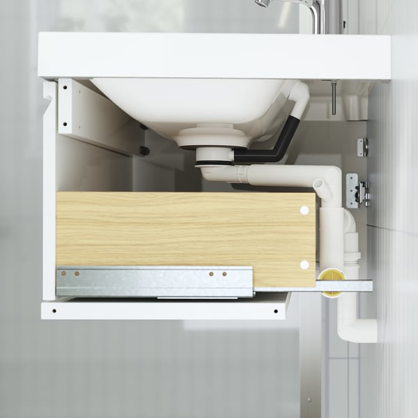 Under-sink drawer open, showing plumbing and storage in bathroom cabinet.