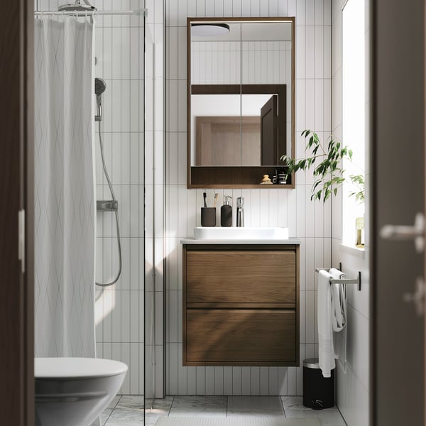 Modern bathroom with ÄNGSJÖN wooden vanity, white countertop, mirror cabinet, and glass shower.