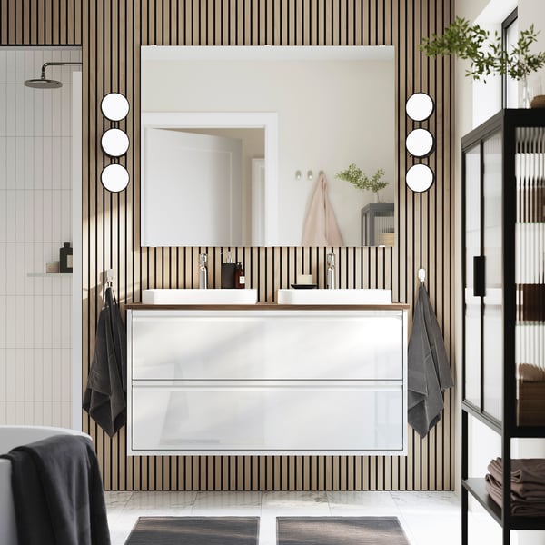 Modern white bathroom: glossy ÄNGSJÖN sink stand, sleek drawers, round mirrors, dark towels. Large.