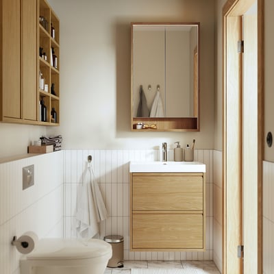 Modern light wood vanity with handles, two drawers, white tiles.