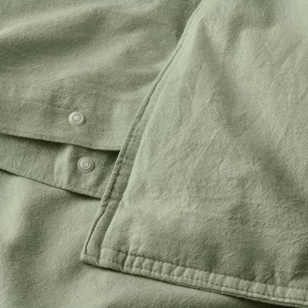 Close-up of light green duvet with button closure, soft cotton texture visible.