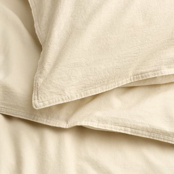 Close-up of crisp, natural fabric of an ÄNGSLILJA duvet cover. Soft, pre-washed cotton with fine stitching visible.