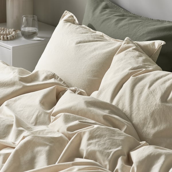 A cosy bed with soft, white cotton duvet and pillows. The duvet cover has a subtle textured finish.