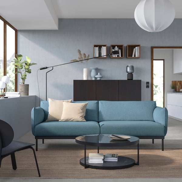 Contemporary living room with teal ÄPPLARYD sofa, black coffee table, and minimalist decor.
