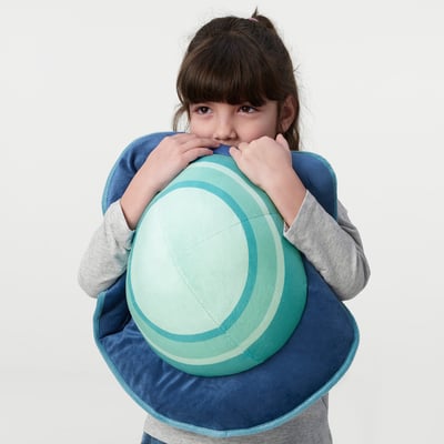 A young girl hugs a large, soft planet-shaped pillow, designed for comfort and support.