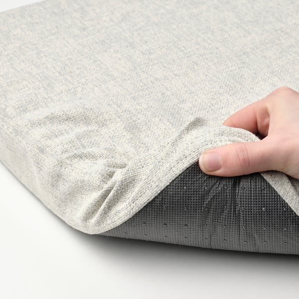 Person holding folded grey fabric cushion with texture.