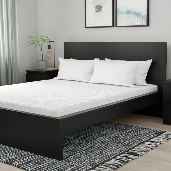 Modern black äkrehamn bed, king-size, stylish headboard, crisp white linens, sleek decor.