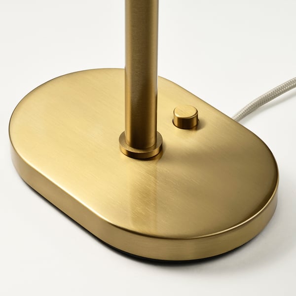 Brushed gold metallic base of modern table lamp with sleek design and subtle silver cord.