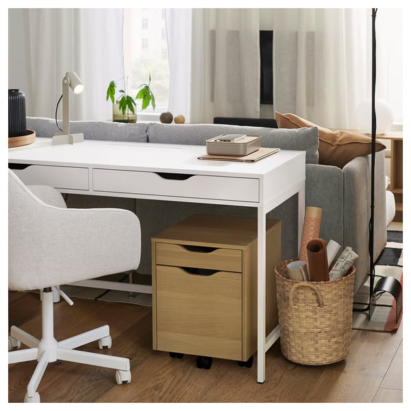 A stylish white ALEX desk with a natural wood drawers unit, featuring a compact storage solution, on castors, neatly organising office supplies.