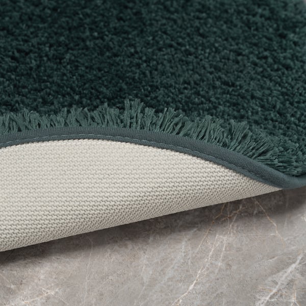 Green bath mat, folded to show thick, plush pile and strong, non-slip backing. Made from recycled polyester.