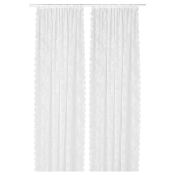 White lace-like curtain panels with floral pattern, sheer, hanging straight.