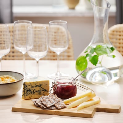 Table set with APTITLIG bamboo cutting board, cheese, crackers, glasses, and decanter.