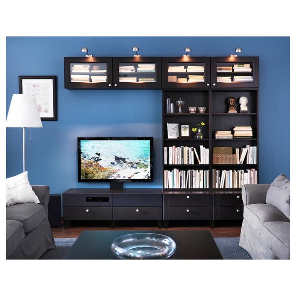 Modern living room with black ÅRSTID tv stand, grey couch, bookshelf with books and decorative items, blue wall, and floor lamp.
