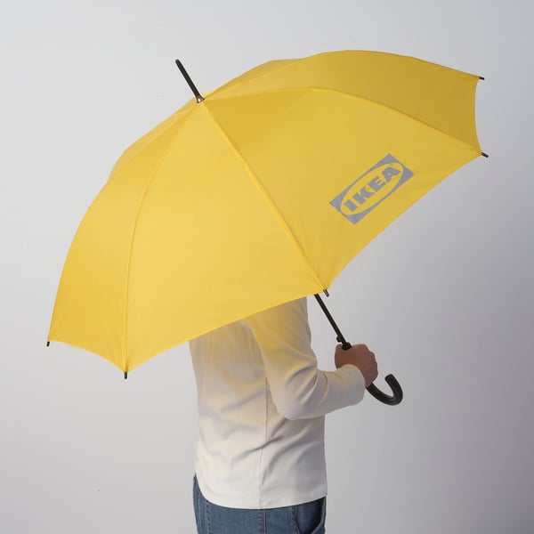 Person holding a bright yellow ikea umbrella, which opens automatically with one hand.