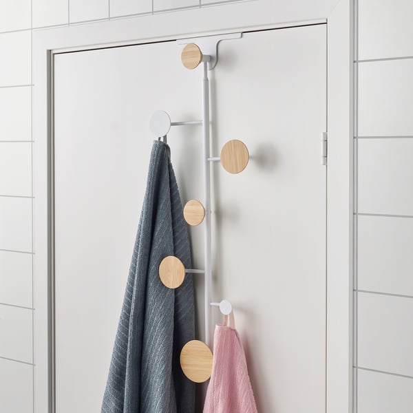 A wall-mounted hanger with wooden knobs holding a grey towel, helping organise and tidy items.