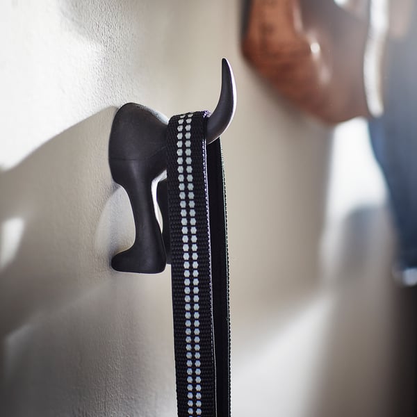 A black, elephant-shaped hook attaches a leash to a wall.