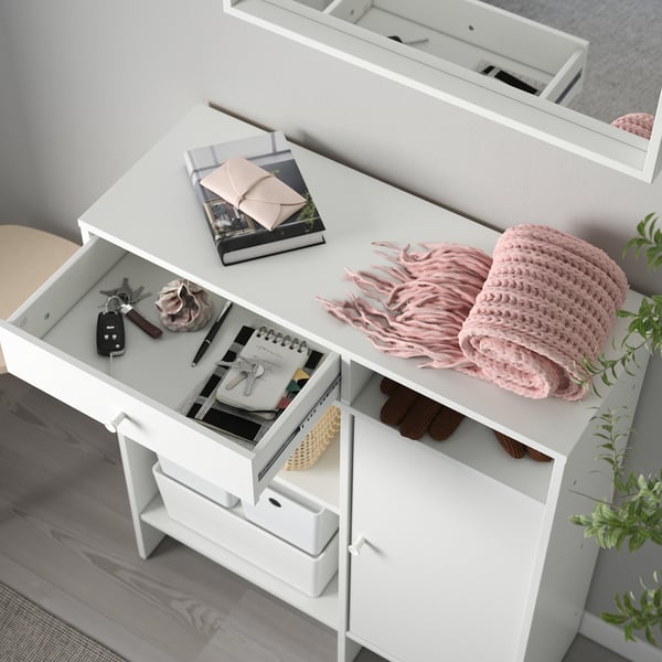 White storage unit with drawers and shelves, displaying books, remote controls, and scarf.