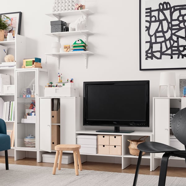 Modern living room BAGGEBO white tv bench, surrounded by white shelves and black chairs.