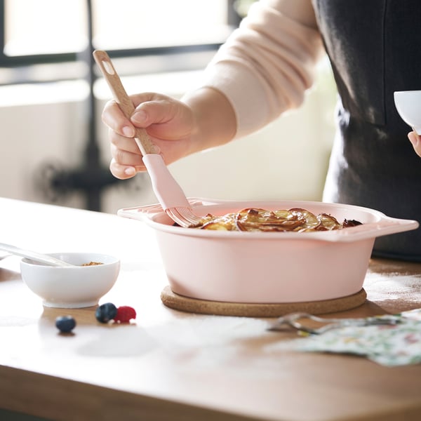 Using pink silicone brush from BAKTIDER set to spread topping on apple tart in pink dish.