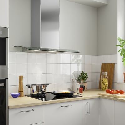 Modern kitchen with BALANSERAD stainless steel hood, wooden countertop, frying pan, utensils, and potted plant.