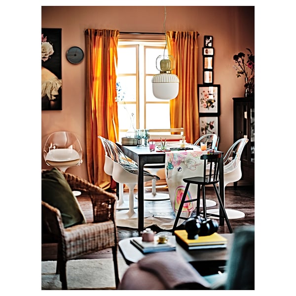 Cosy dining room with orange curtains, white swivel chairs, wooden table, and floral decor.