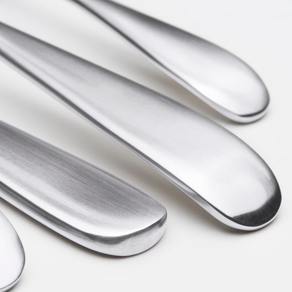 Four polished stainless-steel knives arranged neatly, reflecting light, on a white surface.