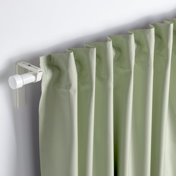 Light-blocking green curtains with neat backside heading tape hang smoothly, showing pleated design.