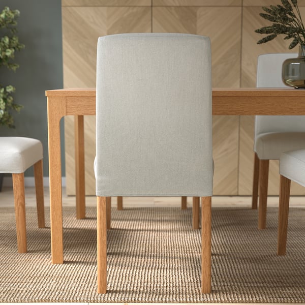 Modern dining chair with grey upholstery and wooden legs at table in cosy room.