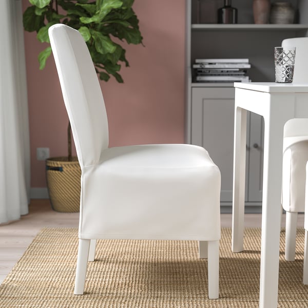 Modern dining chair with white removable cover and wooden legs. Place near desk with decor.